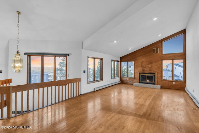 unfurnished living room featuring a chandelier, light wood-type flooring, baseboard heating, and wood walls