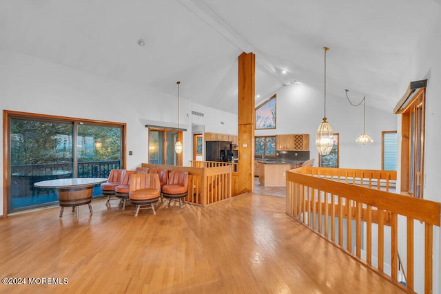 living room featuring light hardwood / wood-style flooring, high vaulted ceiling, beamed ceiling, and a notable chandelier