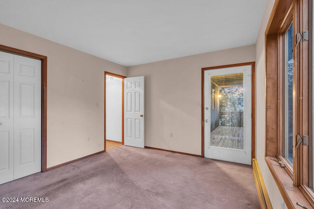 unfurnished bedroom featuring access to exterior, light colored carpet, a baseboard radiator, and a closet