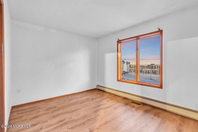 unfurnished room with a baseboard radiator and light hardwood / wood-style floors