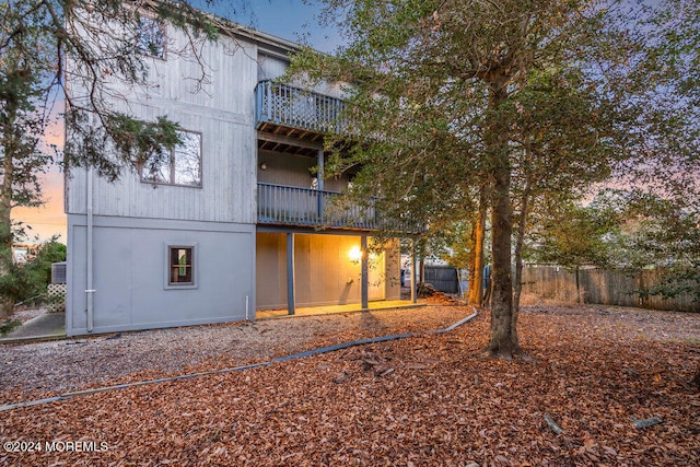 back house at dusk featuring a balcony