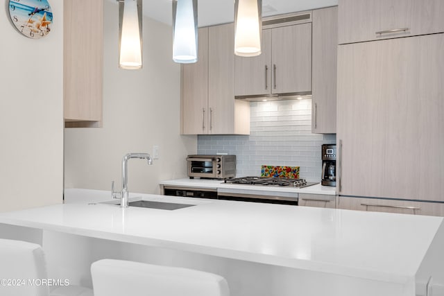 kitchen featuring decorative backsplash, sink, pendant lighting, light brown cabinets, and stainless steel gas stovetop