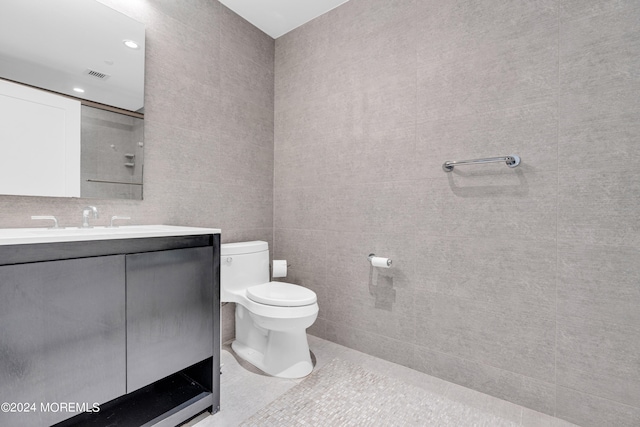 bathroom with tile patterned floors, vanity, tile walls, and toilet