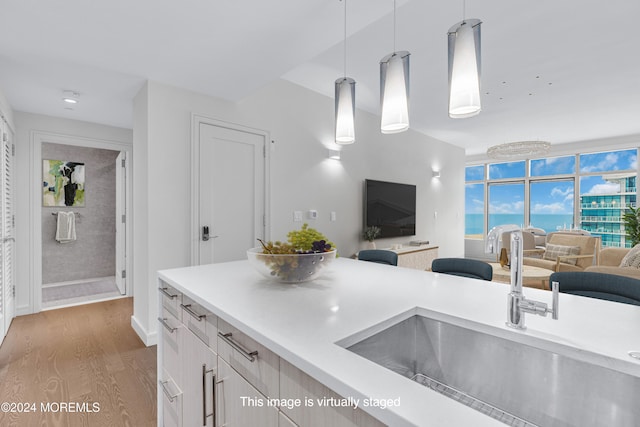 kitchen featuring wood-type flooring, decorative light fixtures, and sink