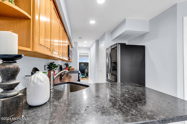 kitchen featuring sink, kitchen peninsula, stainless steel appliances, and dark stone counters