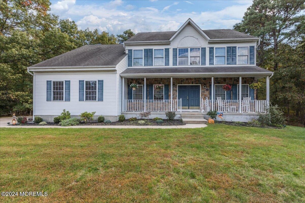 colonial-style house featuring a porch and a front lawn