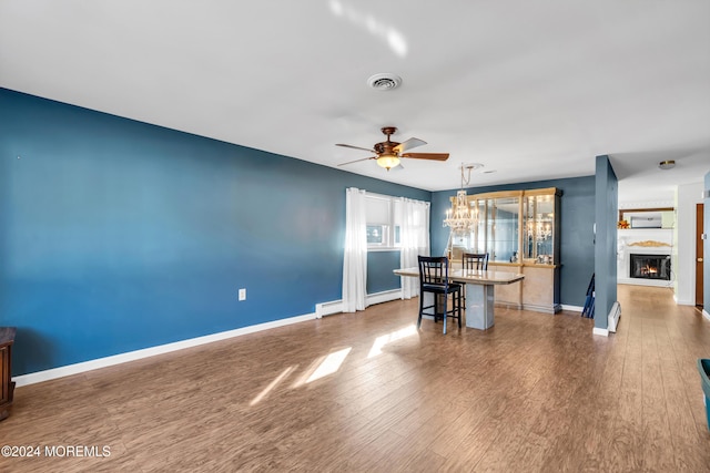 unfurnished dining area with baseboard heating, dark hardwood / wood-style flooring, and ceiling fan with notable chandelier