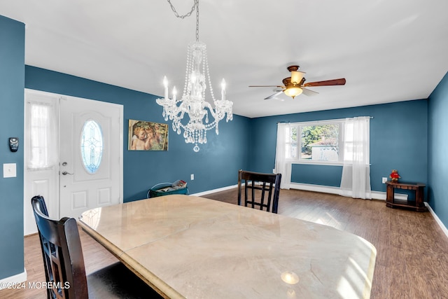 dining area featuring wood-type flooring, ceiling fan with notable chandelier, and a baseboard heating unit