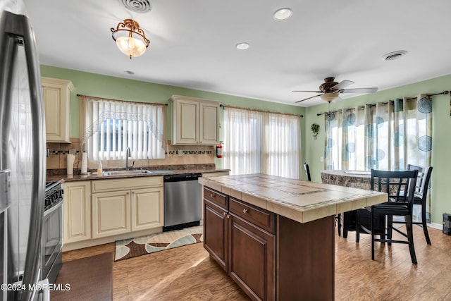 kitchen featuring tile counters, sink, stainless steel appliances, and cream cabinets