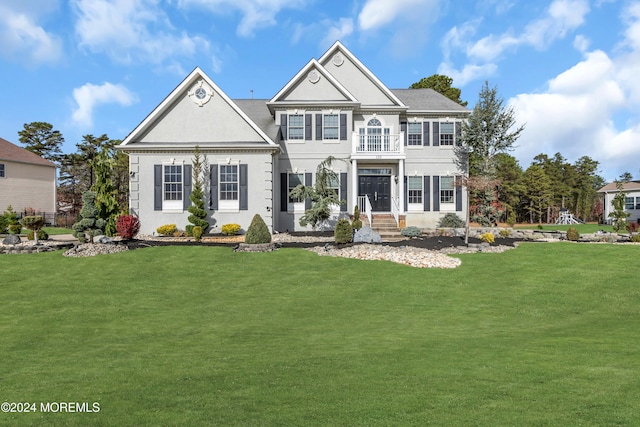 view of front of property featuring a balcony and a front yard