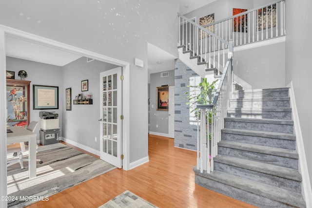 staircase featuring hardwood / wood-style floors and a towering ceiling