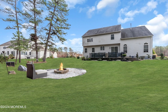 rear view of house with a yard, a fire pit, and a wooden deck