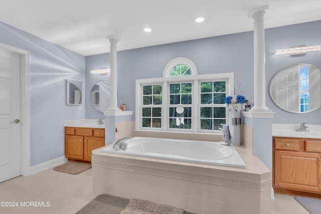 bathroom featuring tile patterned floors, vanity, a relaxing tiled tub, and ornate columns