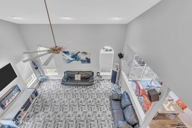 living room featuring light carpet, a towering ceiling, and ceiling fan