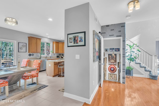 interior space with dishwasher, a center island, sink, light hardwood / wood-style floors, and a kitchen bar