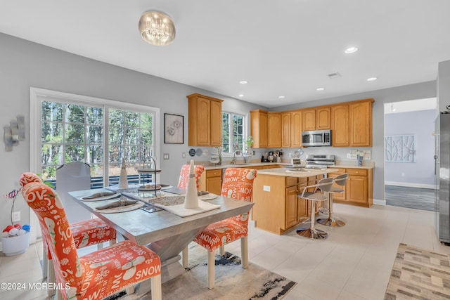 kitchen featuring sink, light tile patterned floors, a kitchen island, a kitchen bar, and stainless steel appliances