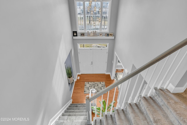 stairway with hardwood / wood-style floors and a towering ceiling