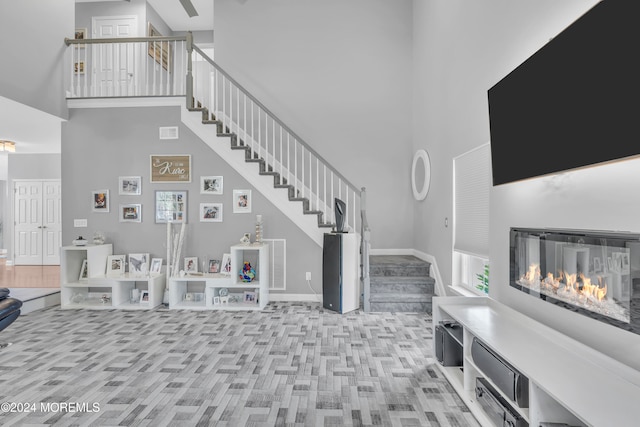 living room with a high ceiling, light wood-type flooring, and a healthy amount of sunlight