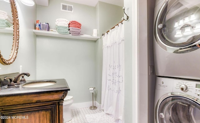 bathroom featuring tile patterned floors, stacked washer / dryer, vanity, and toilet