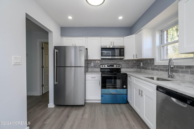 kitchen with light stone counters, white cabinetry, sink, and appliances with stainless steel finishes