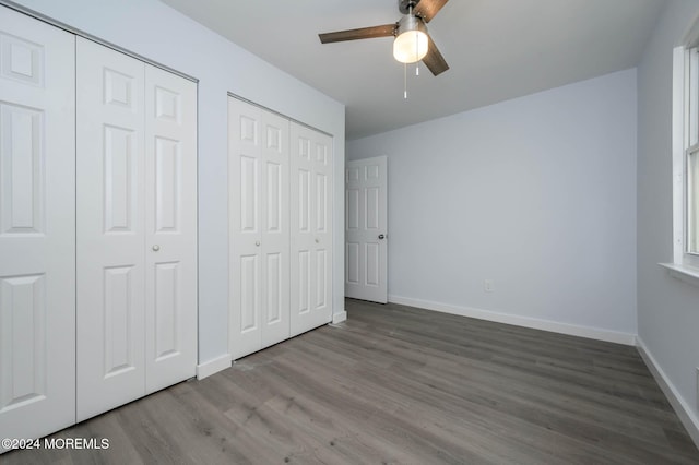 unfurnished bedroom featuring multiple closets, ceiling fan, and hardwood / wood-style flooring