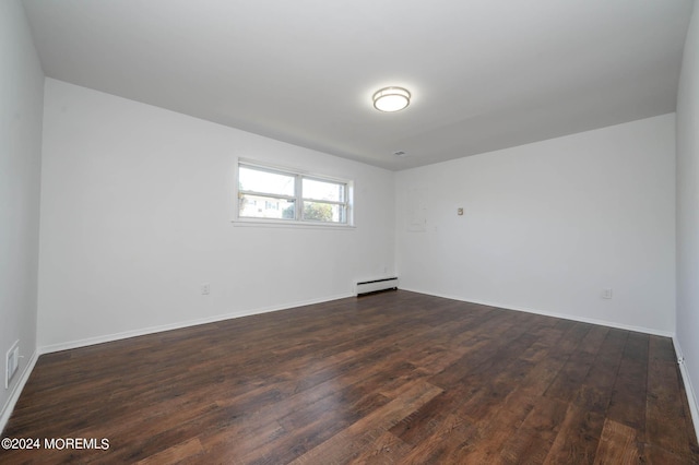 spare room featuring dark hardwood / wood-style flooring and a baseboard heating unit