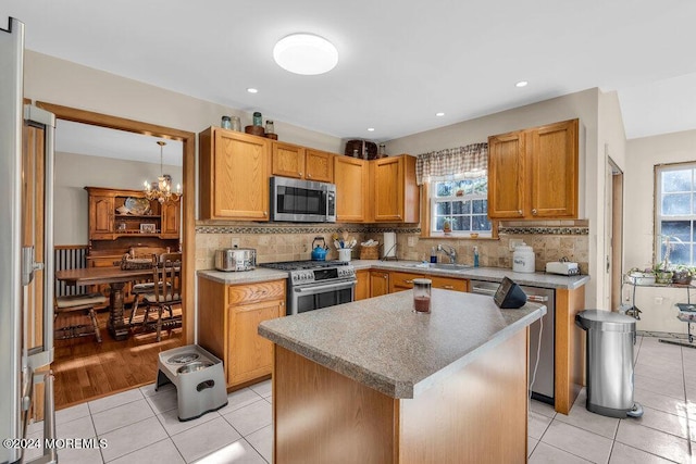 kitchen featuring light tile patterned floors, a center island, stainless steel appliances, and plenty of natural light