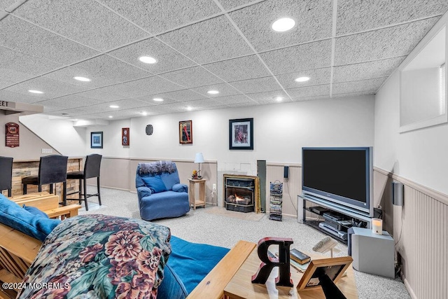 carpeted living room featuring a drop ceiling