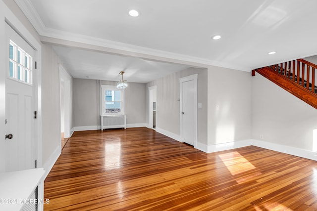 interior space with wood-type flooring, crown molding, radiator, and an inviting chandelier