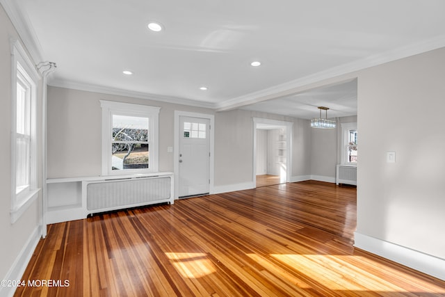 foyer with hardwood / wood-style floors, a notable chandelier, radiator heating unit, and ornamental molding