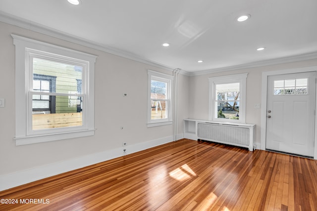 foyer featuring wood-type flooring, radiator, and ornamental molding