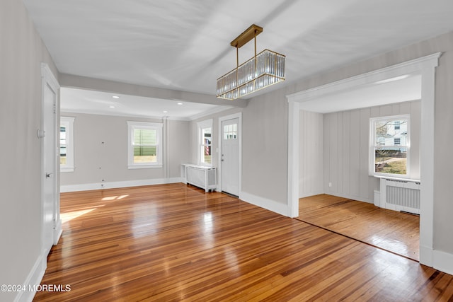 interior space featuring radiator heating unit, a chandelier, plenty of natural light, and hardwood / wood-style flooring