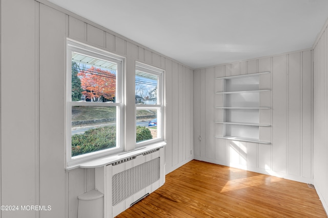 interior space featuring radiator heating unit, built in features, and hardwood / wood-style flooring