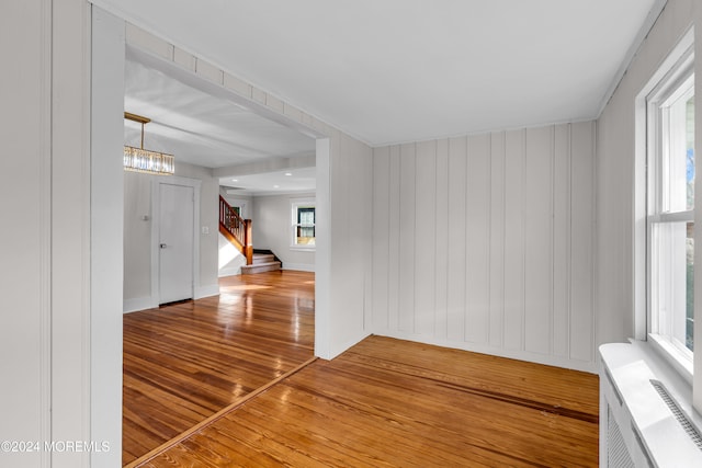 empty room featuring wood-type flooring and an inviting chandelier