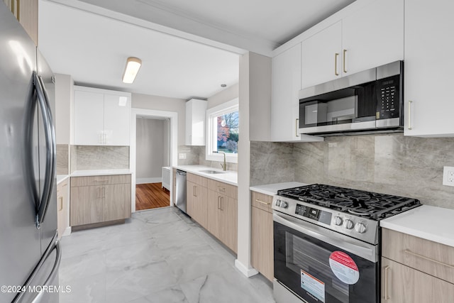 kitchen with sink, light brown cabinets, decorative backsplash, white cabinets, and appliances with stainless steel finishes