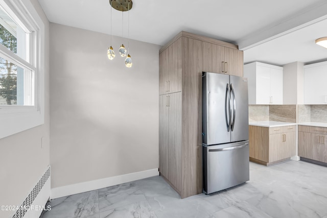 kitchen with tasteful backsplash, radiator, pendant lighting, white cabinetry, and stainless steel refrigerator