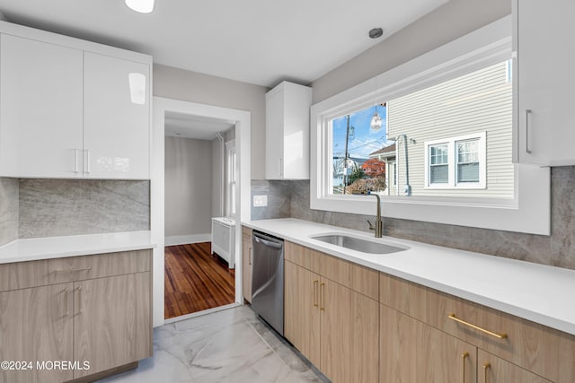 kitchen featuring white cabinetry, sink, stainless steel dishwasher, and decorative light fixtures