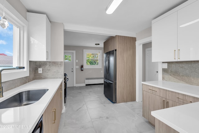 kitchen with radiator heating unit, white cabinetry, sink, and stainless steel refrigerator