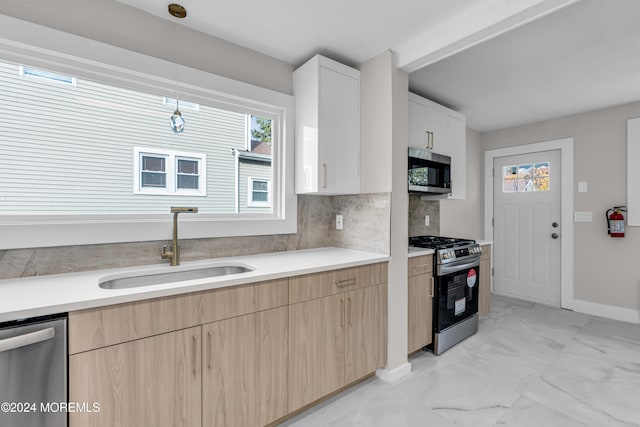 kitchen featuring sink, light brown cabinets, pendant lighting, decorative backsplash, and appliances with stainless steel finishes