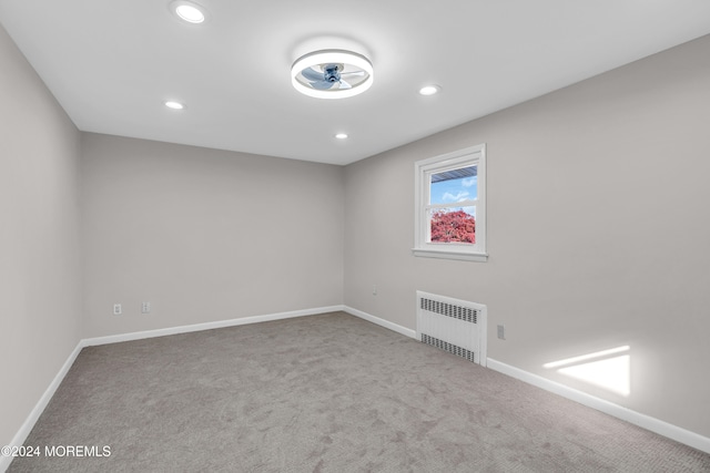 carpeted empty room featuring radiator heating unit