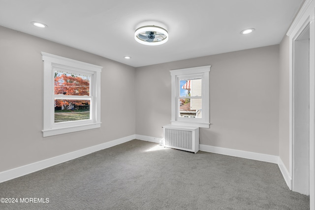 unfurnished room featuring radiator heating unit and carpet floors