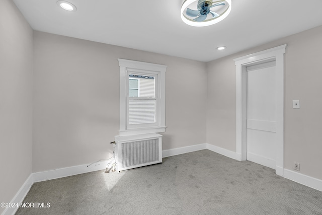 carpeted spare room with ceiling fan and radiator heating unit