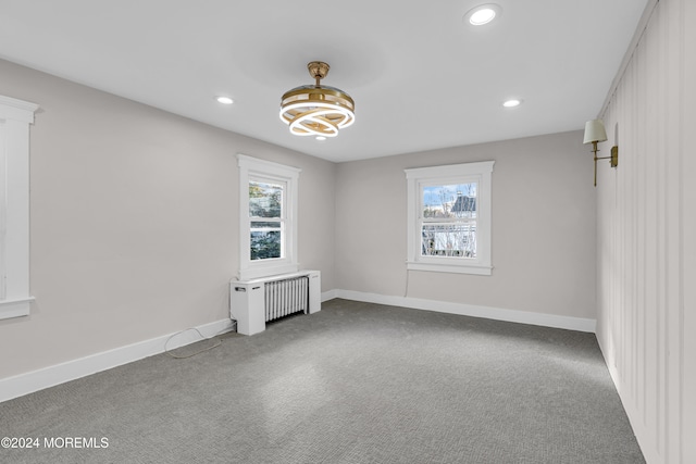 empty room with carpet, radiator heating unit, and plenty of natural light