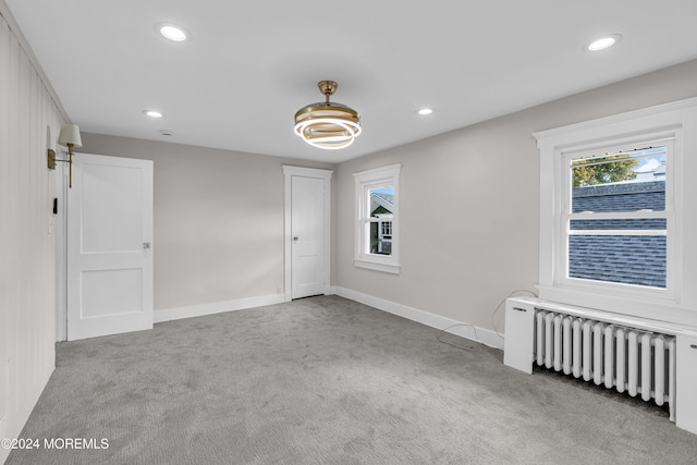 unfurnished room with light colored carpet and radiator