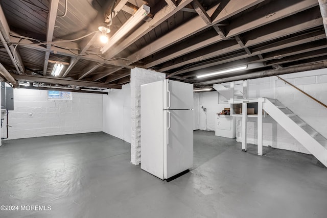 basement featuring white refrigerator, washer / clothes dryer, and electric panel