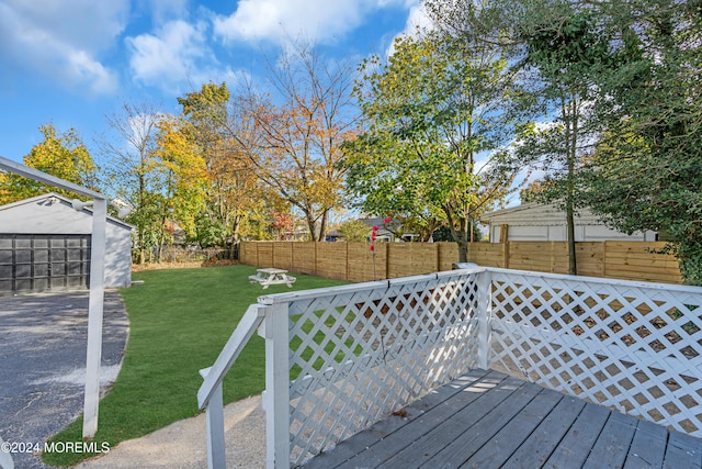 wooden deck featuring a yard, an outbuilding, and a garage