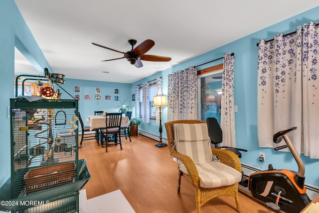 living area featuring light hardwood / wood-style flooring, ceiling fan, and a baseboard heating unit