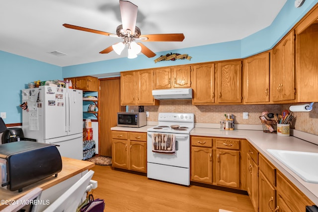 kitchen featuring ceiling fan, white appliances, sink, and light hardwood / wood-style flooring