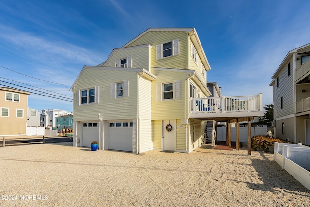 rear view of property featuring a wooden deck and a garage