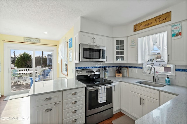 kitchen featuring sink, stainless steel appliances, light stone counters, hardwood / wood-style floors, and white cabinets